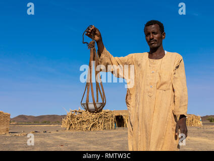 Die Beduinen der arabischen Mann mit einem Leder Werkzeug für Küche, nördlichen Staat, Bayuda Wüste, Sudan Stockfoto