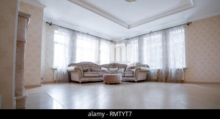 Ecke ein sehr modernes Wohnzimmer mit einem großen grauen Sofa stehen zwei Fenster Stockfoto