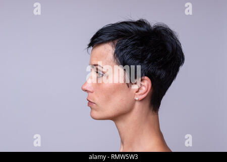 Seitenansicht Porträt einer Frau, die in kurzen dunkleres Haar über neutralen Hintergrund Stockfoto