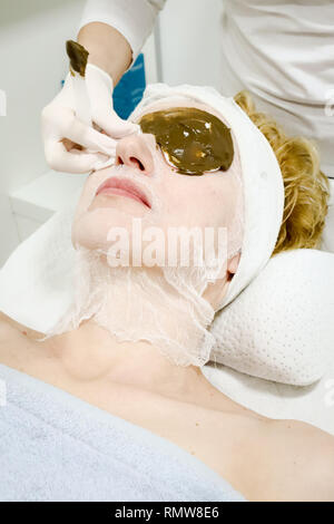 Kosmetikerin Arbeitnehmer anwenden kosmetische Gesichtsmaske von Meer ​​Algae für Anti Aging und Hydratation der Haut für weibliche Kunden im Beauty Salon Stockfoto