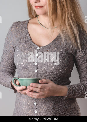 Junge Frau mit langem Haar mit einem türkis Teetasse. Stockfoto