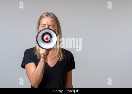 Wütende Frau in ein Handheld Megaphon ein Konzept von Aktivismus, Streik, Demonstration, Protest oder Sprechen in der Öffentlichkeit über Graues kreischend mit Kopie Raum Stockfoto