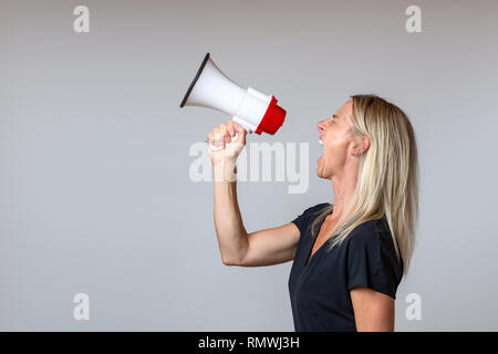 Junge Frau schreien in ein Megaphon, Seitenansicht auf weiß konzeptionelle einer Rallye oder protest Stockfoto