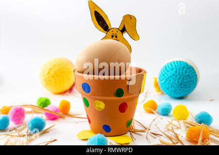 Ostereier in verschiedenen Farben auf dem Tisch liegt neben der Grünen und der Hase Stockfoto