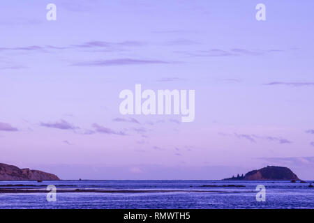Der Himmel ist klar über dem Strand wie die Sonne in Gisborne, Neuseeland verschwindet. Stockfoto
