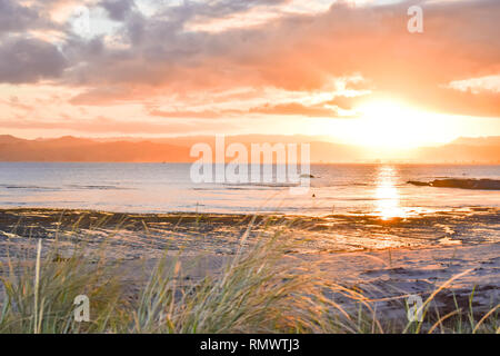 Ein weiches Sonne im Hintergrund über das Meer und die Berge in Gisborne, Neuseeland. Stockfoto