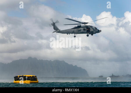 Us Marine schweren Helikopter Squadron 463 und US-Segler mit Hubschrauber Maritime Strike Squadron (HSM) 37 warten für die Luftbrücke von MH-60R ist HSM-37 Seahawk Hubschrauber während einer wasserrettung Schulungsveranstaltung aus dem Ufer des Marine Corps Base Hawaii, Jan. 30, 2019. Zweck der Ausbildung ist es, Marinesoldaten und Matrosen mehr in Wasser Rettungsmaßnahmen geübt. (U.S. Marine Corps Foto von Lance Cpl. Porfirio Gonzalez) Stockfoto