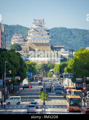 Ein Blick auf Ootemae-dori (Ootemae Straße), der Hauptstraße, und Himeji Castle (Himeji-jo) steigen in den Hintergrund, in Himeji, Hyogo Präfektur, Japan. Stockfoto