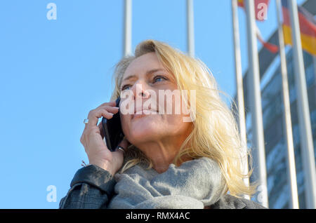Vor der nationalen Flaggen mit einem Telefonanruf in der Nähe zu sehen, Geschäftsfrau Stockfoto