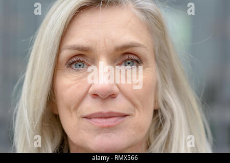 Close up 7/8 Portrait von einem attraktiven blauen Augen reife Frau mit langen blonden Haaren direkt auf das Objektiv Stockfoto