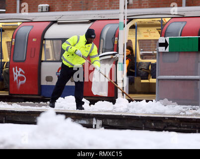 Bild zeigt: Schnee und Schneeregen behindert Pendler auf ihre Arbeit heute im East Finchley, London Mann Clearing Plattform an der tube station pic von Stockfoto