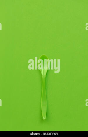 Grüne Plastiklöffel auf einem grünen Abstrakt Hintergrund Stockfoto