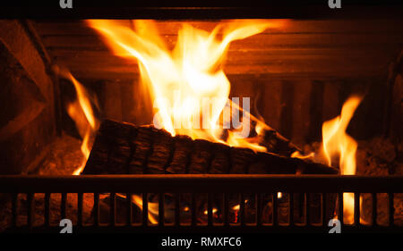 Brennholz brennt im Kamin mit einer hellen Flamme bei Nacht Stockfoto