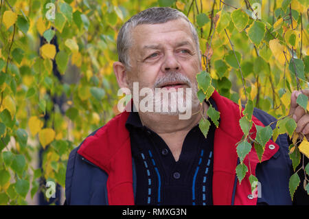 Schöne Outdoor Portrait von älteren Menschen gegen herbstliches Laub von Branchy Birke Stockfoto