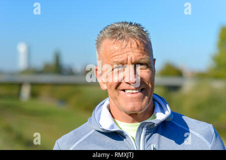 Portrait von lächelnden sportlicher Mann vor einem grünen Park Stockfoto