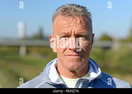 Ernster Mann mit einem rätselhaften Ausdruck steht in einem Park starrte mit offenen Augen Stockfoto