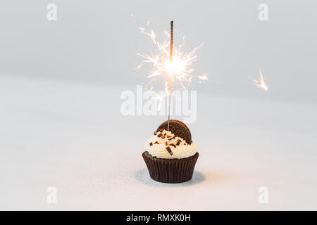 Essen, Party und Urlaub Konzept - Geburtstag Cupcake mit Wunderkerzen auf weißem Hintergrund Stockfoto