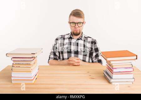 Menschen, Wissen und Bildung Konzept - Müde männliche Kursteilnehmer am Tisch sitzen mit Bergen von Büchern und will nicht bis zu Studie Stockfoto