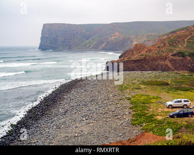 Autos an einem Surf Spot am Strand von Arrifana, einem kleinen Dorf beliebt bei Surfern im Süden von Portugal westliche Küste. Stockfoto