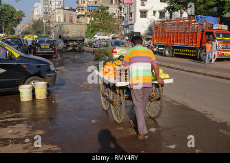 Eine Frucht Anbieter schiebt seinen Wagen voll von Waren durch Grant Road, Mumbai, Indien Stockfoto