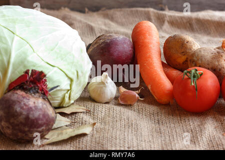 Rohes Gemüse für Zuckerrüben Suppe Borschtsch. Weisskohl, Rüben, Karotten, Kartoffel, Tomate, auf Holzbrett Knoblauch Stockfoto
