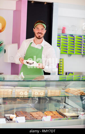 Süßwaren-Verkäufer, zeigt schöne Kuchen auf Teller Stockfoto