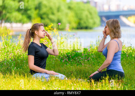 Yoga im Park - Meditation und Atemübungen mit einem erfahrenen Trainer, Porträt von zwei Frauen Stockfoto