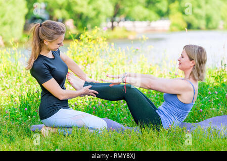 Yoga Übung mit einem individuellen erfahrener Trainer im Park Stockfoto