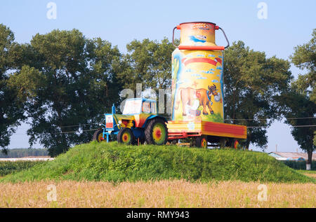 Eingerichtet malen heiter Traktor mit einem großen Milch kann in einem Trailer auf einem Hügel im Dorf. Belarus. Stockfoto