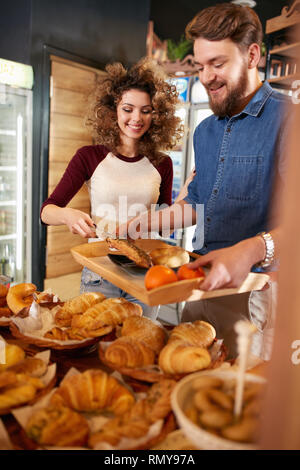 Mädchen dient Käufer mit frischem Gebäck in der Konditorei. Stockfoto