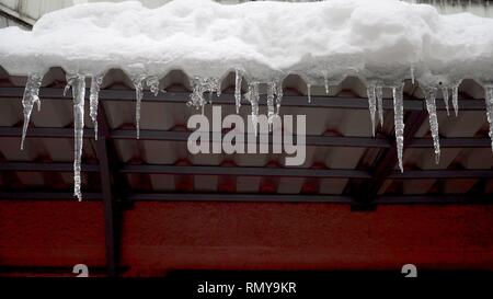 Winter Eiszapfen schmilzt auf dem Dach unter der Frühlingssonne und tropft aus ihre Tipps Stockfoto