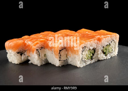 Uramaki philadelphia Rolle mit Lachs, Gurke und Rahm Käse gefüllt. Philly rollt auf schwarzen Stein Schiefer Teller serviert. Stockfoto