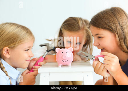 Kinder mit Schraubendreher, Zange und Hammer durch den Pink Pig piggy Bank auf weißem Hintergrund Stockfoto