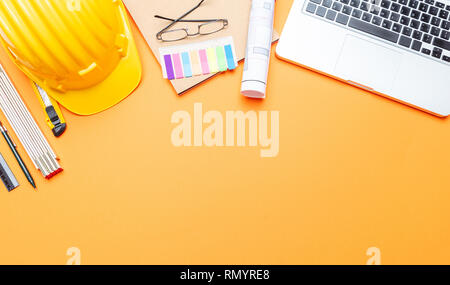 Architekt Ingenieur Baustelle Büro Schreibtisch. Projektentwürfe, gelben Schutzhelm und Computer Laptop auf orange Farbe, Kopieren Raum Stockfoto