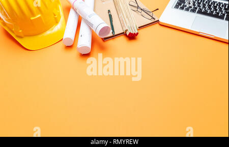 Architekt Ingenieur Baustelle Büro Schreibtisch. Projektentwürfe, gelben Schutzhelm und Computer Laptop auf orange Farbe, Kopieren Raum Stockfoto