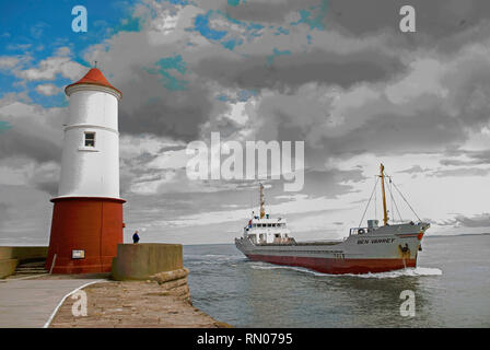 Redundante Leuchtturm auf der Mole in Berwick-upon-Tweed, Northumberland, Großbritannien, mit Cargo Schiff nähert sich Dock Stockfoto