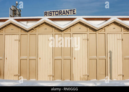 Blick auf einige "Kabinen" (Strandhütten) im Schnee in Riccione, in der Emilia Romagna, Italien. Schild "Ristorante" (Restaurant) im Hintergrund. Stockfoto