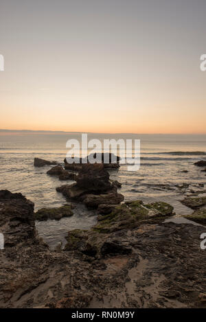 Ein Sonnenaufgang zwischen den Felsen von Oropesa del Mar, Spanien Stockfoto