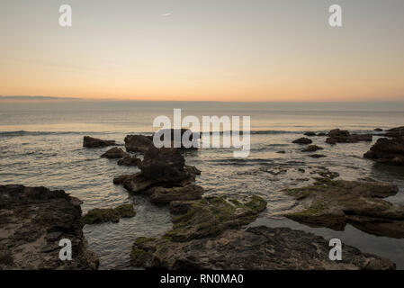 Ein Sonnenaufgang zwischen den Felsen von Oropesa del Mar, Spanien Stockfoto