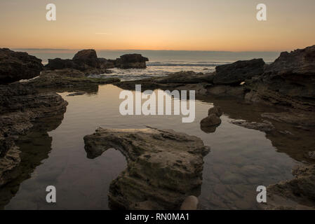 Ein Sonnenaufgang zwischen den Felsen von Oropesa del Mar, Spanien Stockfoto