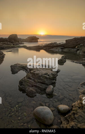 Ein Sonnenaufgang zwischen den Felsen von Oropesa del Mar, Spanien Stockfoto