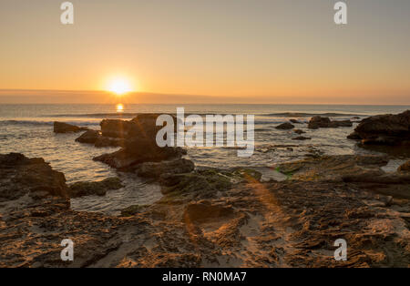 Ein Sonnenaufgang zwischen den Felsen von Oropesa del Mar, Spanien Stockfoto