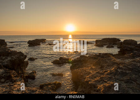 Ein Sonnenaufgang zwischen den Felsen von Oropesa del Mar, Spanien Stockfoto
