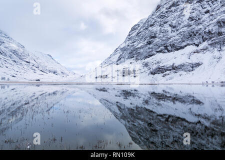 Snowy Achtriochtan Reflexionen in Loch Ness, Glencoe, Scottish Highlands, Schottland Großbritannien im Januar Stockfoto