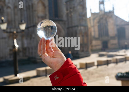 Runde Glaskugel auf den Fingern einer Frau vor York Minster, North Yorkshire, England, Großbritannien. Stockfoto