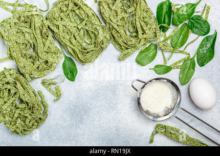 Raw hausgemachte italienische grüne pasta Tagliatelle. Trockene Nudeln und Zutaten (Spinat, Mehl, Ei). Selektiver Fokus, Ansicht von oben, kopieren Raum Stockfoto