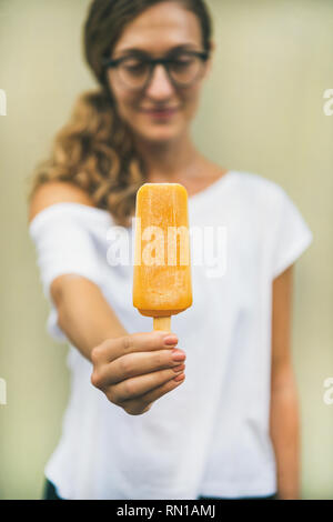 Gesunde mango Zitrusfrüchte Eis Popsicle in der Hand der Frau Stockfoto