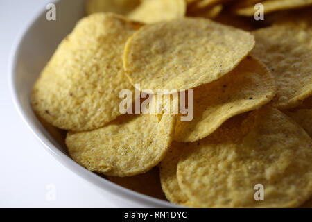 Nahaufnahme von einer Schüssel mit köstlichen und knackigen Nachos. Nachos goldgelb sind und die Schüssel und Tabelle sind weiß. Auf einem weißen Tisch fotografiert. Stockfoto