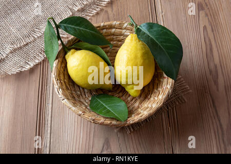 Zwei frische Zitronen mit Blättern in einem Korb Stockfoto