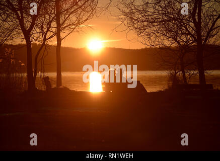 München, Deutschland. 16. Februar 2019, Bayern, München: Wanderer genießen die letzten Strahlen der untergehenden Sonne im Starnberger See. Foto: Angelika Warmuth/dpa Stockfoto